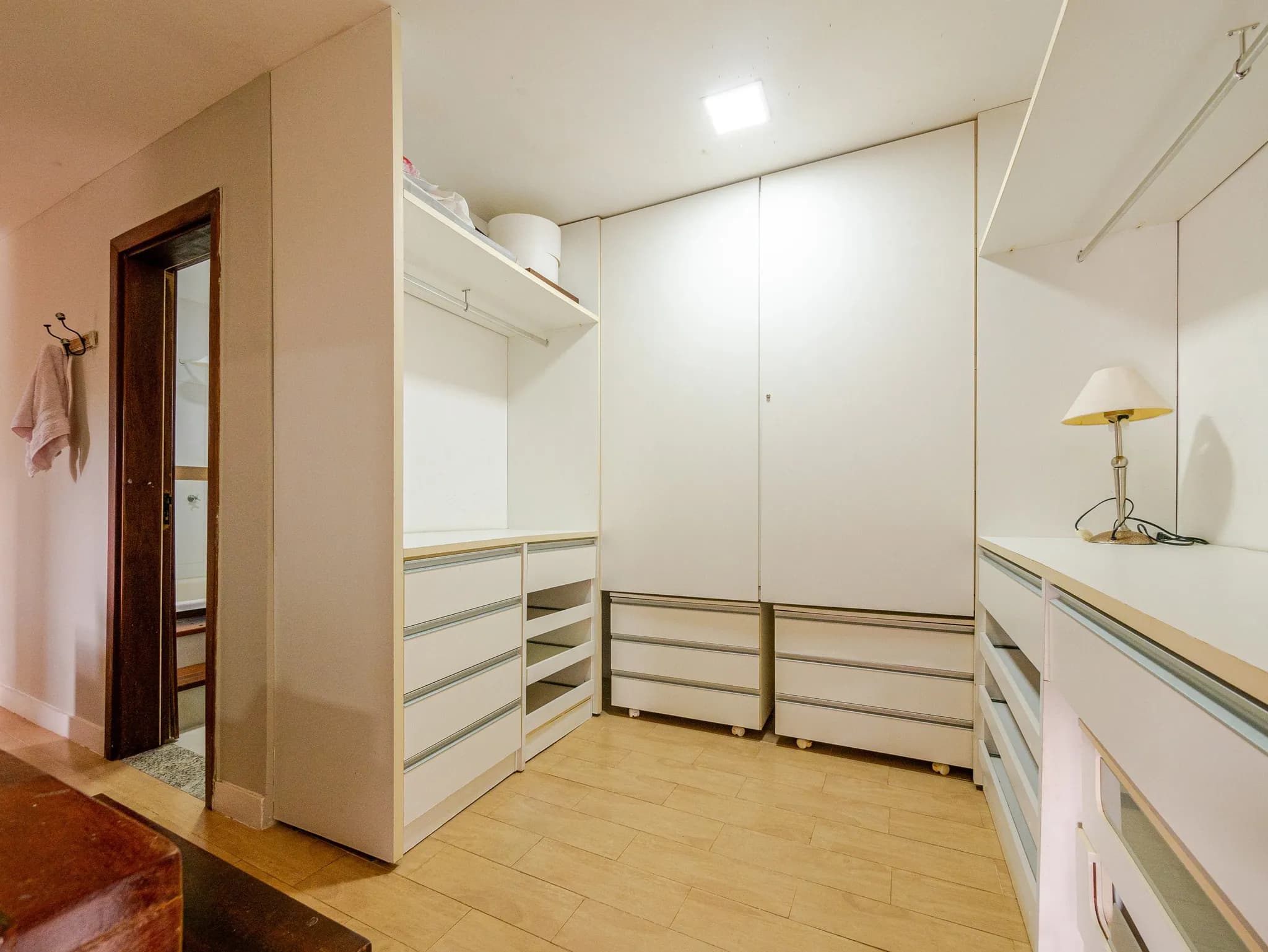 Closet da suíte master com armários brancos e gavetas